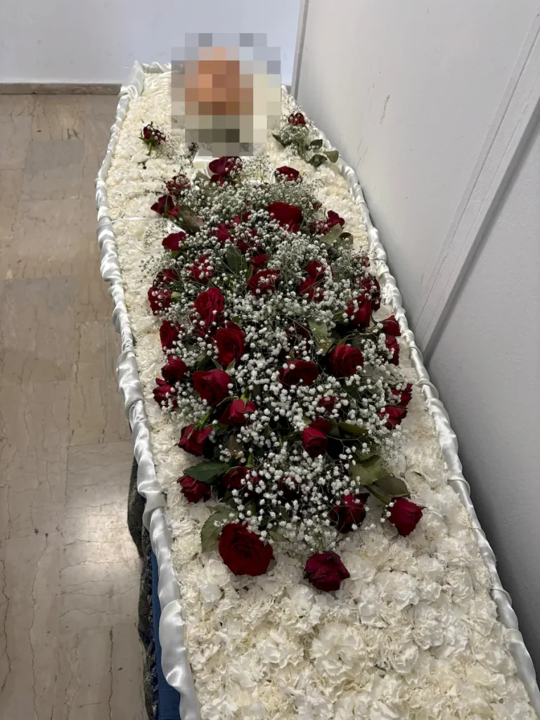 Στολισμός φέρετρου πολυτελείας με λευκά και κόκκινα άνθη.