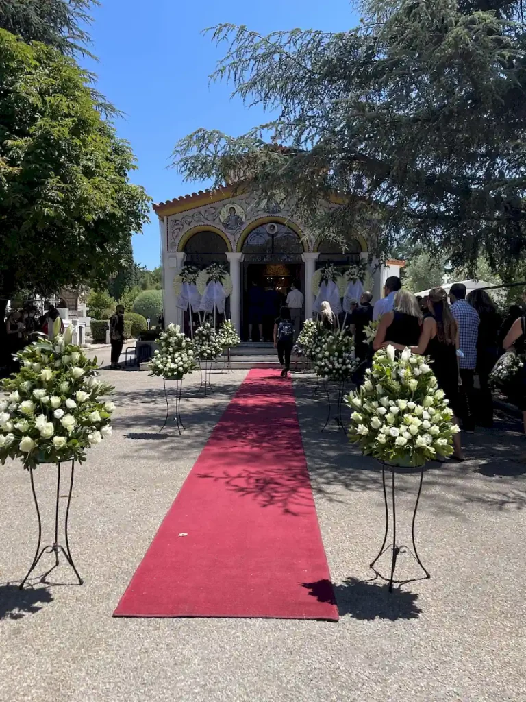 Στολισμένη είσοδος Ιερού Ναού στο Κοιμητήριο Κηφισιάς με χαλιά και ανθοστήλες.