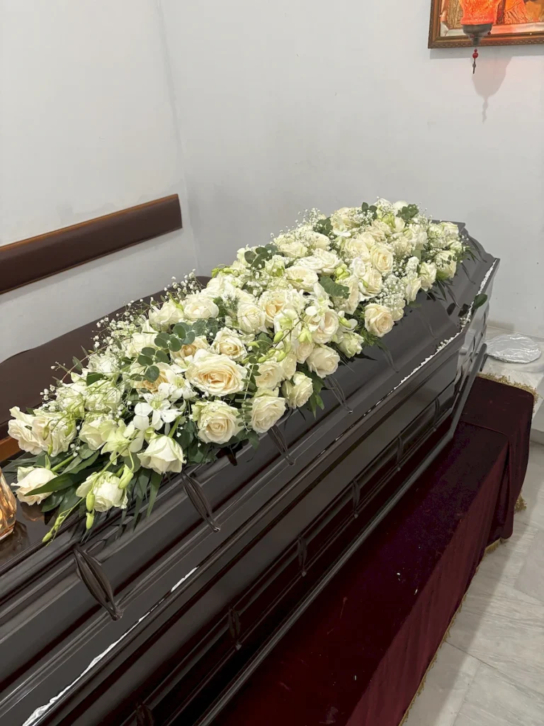 Φέρετρο “Δάκρυ” με πολυτελή στολισμό και λευκά άνθη στο Κοιμητήριο Ζωγράφου.